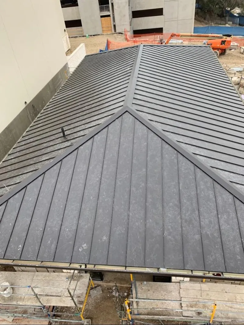 Commercial metal roof construction with crane equipment in North Reading